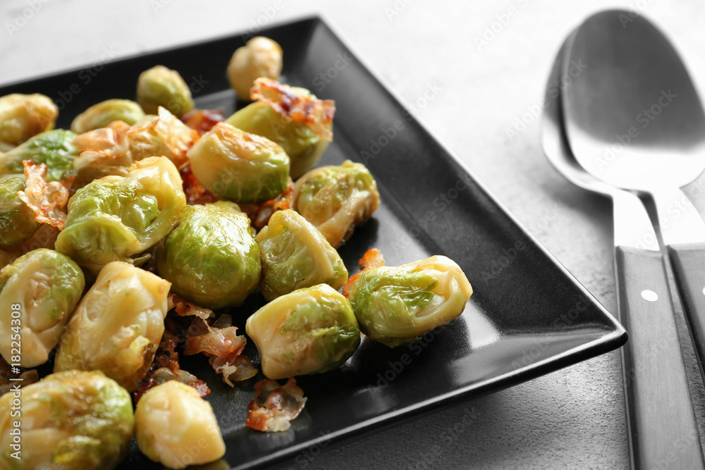 Plate with Brussels sprouts and bacon on table, closeup