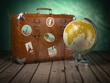 Old suitcase with globe on wood  background. Travel or tourism concept.
