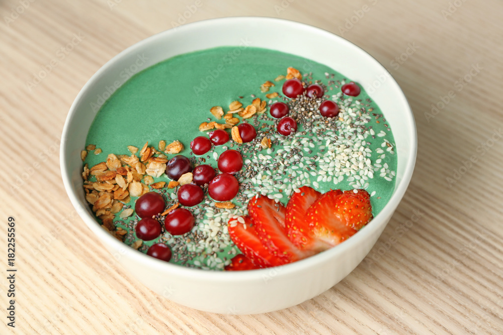 Bowl with yummy spirulina smoothie on wooden table. Healthy vegan food concept