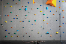 Grey Wall With Climbing Holds And Ropes In Gym