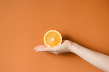 Tasty orange in a hand. holding a orange isolated on a colored background