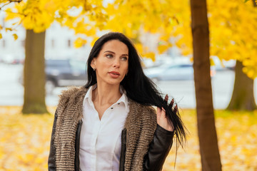 portrait of a beautiful young girl walking along the autumn park in fashionable clothes