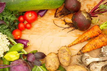 Wall Mural - Harvest of fresh vegetables on a wooden background, in garden background. Top view. Garlic, beet, zucchini, kohlrabi, cauliflower, pepper, tomatoes, potatoes, basil, cucumber, dill.