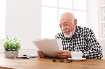 Cheerful senior man looking photos, copy space