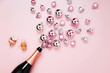 Champagne bottle with pink and silver christmas balls. Flat lay, top view trendy holiday concept.
