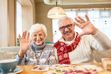 Canvas Print - Portrait of smiling  senior couple looking at camera waving happily while enjoying dinner in cafe