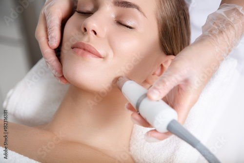 Fotografía Close up of beautician hand making ultrasound facial procedure by special equipment