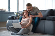 © Yakobchuk Olena - I want this one. Full length portrait of happy pregnant woman pointing on laptop screen and smiling. Her husband is looking there with interest while massaging female shoulders at home