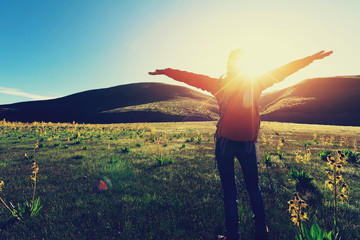 Wall Mural - happy woman hiker raised arms  in sunrise mountains