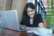 © mansong - businesswoman smiling and thinking in front of laptop while sitting at co-working space office to manage her coffee shop.Small business pondering over ideas for new business project,vintage tone