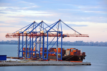 Ship under crane at sunset