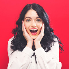 Surprised and excited young woman posing on a solid background