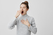 © Cookie Studio - Tired woman yawning covering open mouth with hand need rest. Young female worker being sleepy head can't wake up having insomnia. Chain reaction