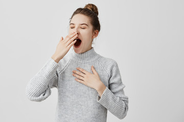 tired woman yawning covering open mouth with hand need rest. young female worker being sleepy head c