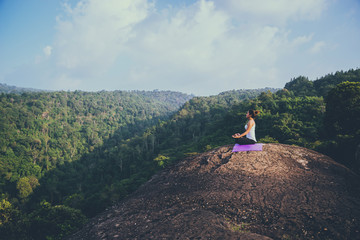 Asian women relax in the holiday. Play if yoga. On the Moutain rock cliff. Nature of mountain forests in Thailand