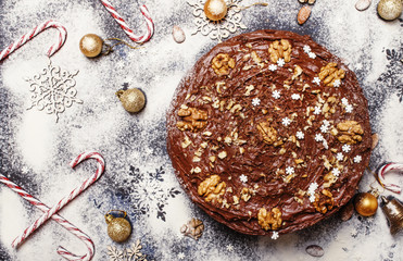 Wall Mural - Christmas chocolate cake with nuts, white snow background with new yaers decoration, top view