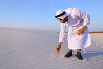 Wall Mural - Muslim man develops sand along wind and standing in middle of de