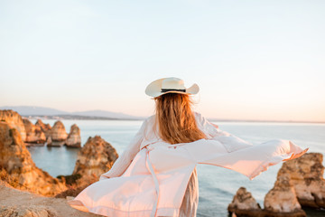 Woman enjoying great view on the rocky coastline during the sunrise in Lagos on the south of Portugal