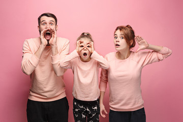 Surprised young family looking at camera on pink