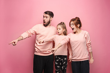 Surprised young family on pink