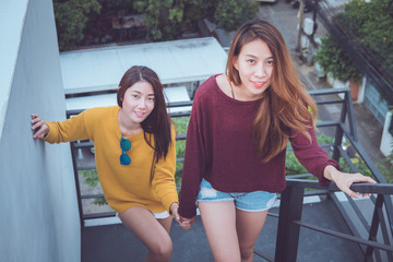 LGBT. Lesbian couple together concept. Couple of young asian women walking up the stairs to top roof.