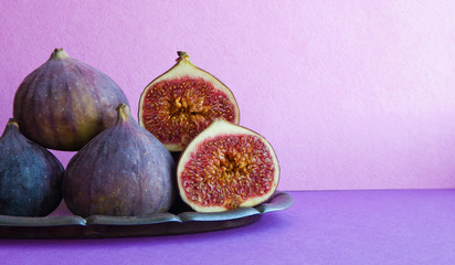 Bright still life organic fig fruits on an old tray, beautiful purple violet background. Selective focus photography, copy space.