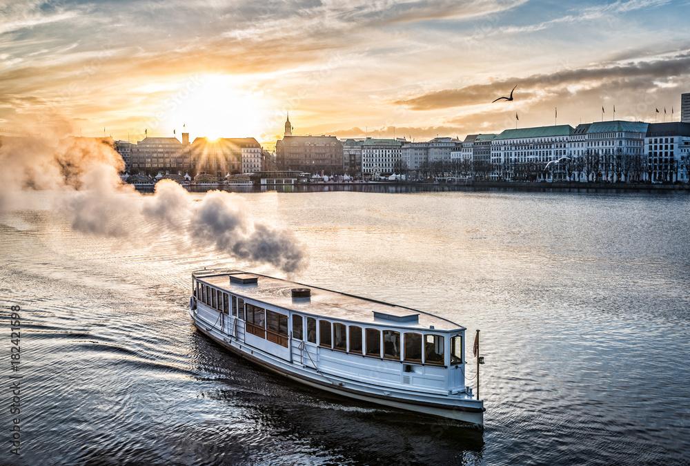 steamboat on Alster Lake in Hamburg, Germany with cityscape in background during sunset - obrazy, fototapety, plakaty 