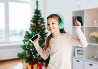 Canvas Print - girl with smartphone and headphones at christmas