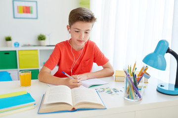 Wall Mural - student boy in earphones writing to notebook