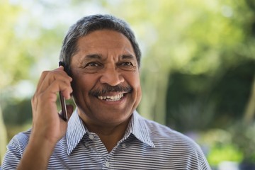 smiling senior man talking on mobile phone at porch