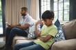 © WavebreakMediaMicro - Upset boy sitting on sofa with father holding digital tablet at