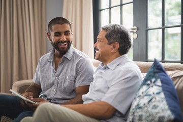 Happy man with his father sitting on couch at home