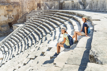 Wall Mural - Two young girls student traveler enjoy a tour of the ancient Greek amphitheater