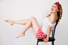 A Pin-up Girl Sits On A Chair With Bare Legs