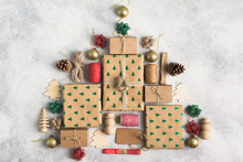 Christmas Tree Made Of Brown Present Boxes, Red And Green Bows, Pine Cones, Jute Twine, Wooden Ornaments On The Light Background, Top View, Copy Space For Text
