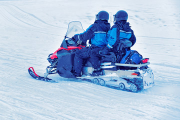 Wall Mural - Couple riding snowmobile on frozen lake at winter Rovaniemi