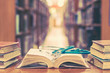 © Chinnapong - Old book in library with stethoscope on open textbook, stack piles of texts on reading desk, and aisle of bookshelves in  study class room background for medical school education learning concept