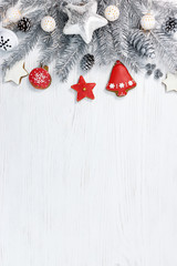 silver christmas fir tree branches with decorations and homemade gingerbreads on white wooden backgr