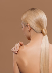 rear view of girl with beautiful long blonde hair and naked back isolated on beige