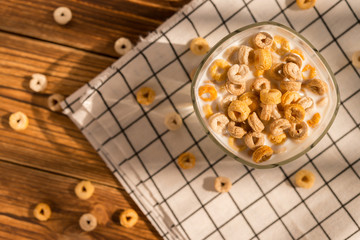 Wall Mural - top view cup of milk with cereal rings in a sunny morning as healthy breakfast