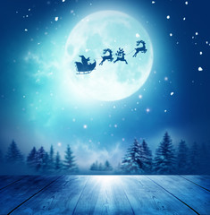 Wall Mural - merry christmas and happy new year greeting card with table. santa and his sleigh flying over snowy 