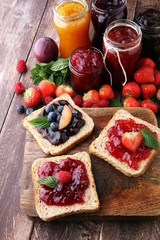 Wall Mural - Sandwiches with plum, strawberry jam and fresh fruits on wooden background