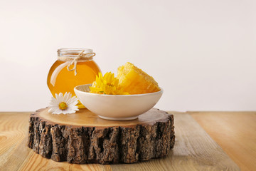 Sticker - Aromatic honey in glass jar and dish with honeycomb on table against light wall