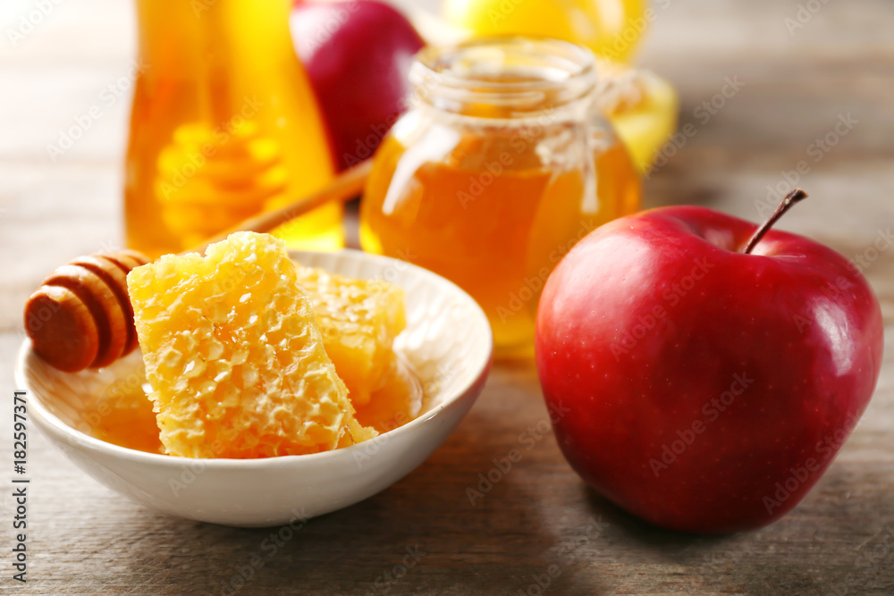 Honeycomb in bowl and apple on wooden table