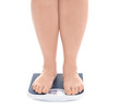 Overweight woman measuring her weight using scales on white background