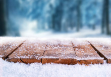Wooden Table, Bench Covered In Snow With A Christmass, Wintery And Snowy Background With Space To Add Products And Text.