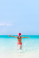 Wall Mural - Christmas sun vacation Santa Claus hat woman happy on cruise travel holidays beach in Caribbean holiday getaway destination for honeymoon.