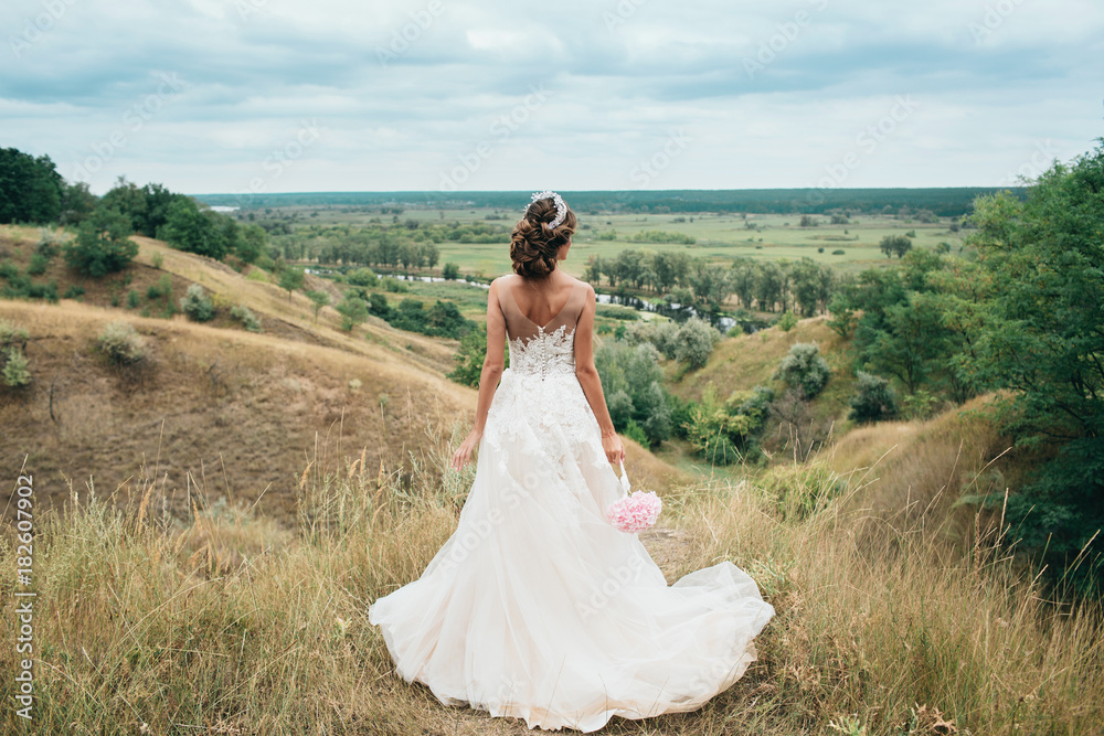 A young girl, the bride in a long wedding dress, is turned her back and ...
