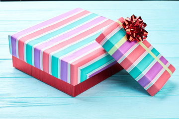 Two boxes with Christmas presents. Different sizes boxes wrapped in multicolored striped paper on blue wooden background. Holidays and celebrations concept.