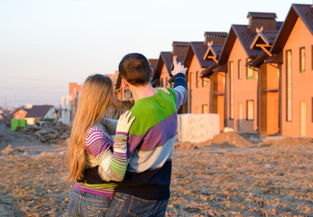 Wall Mural - Rear view of young couple looking at their new house.